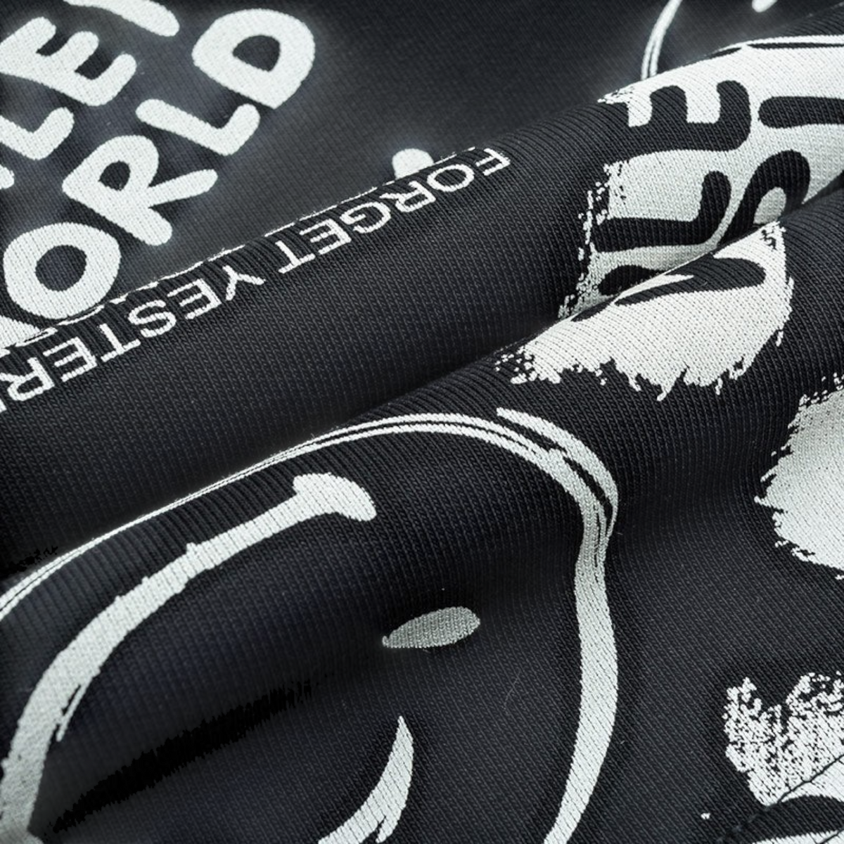 Close-up of FRG black knit fabric with white graphic text and smiley face print, showing soft cotton-blend texture.