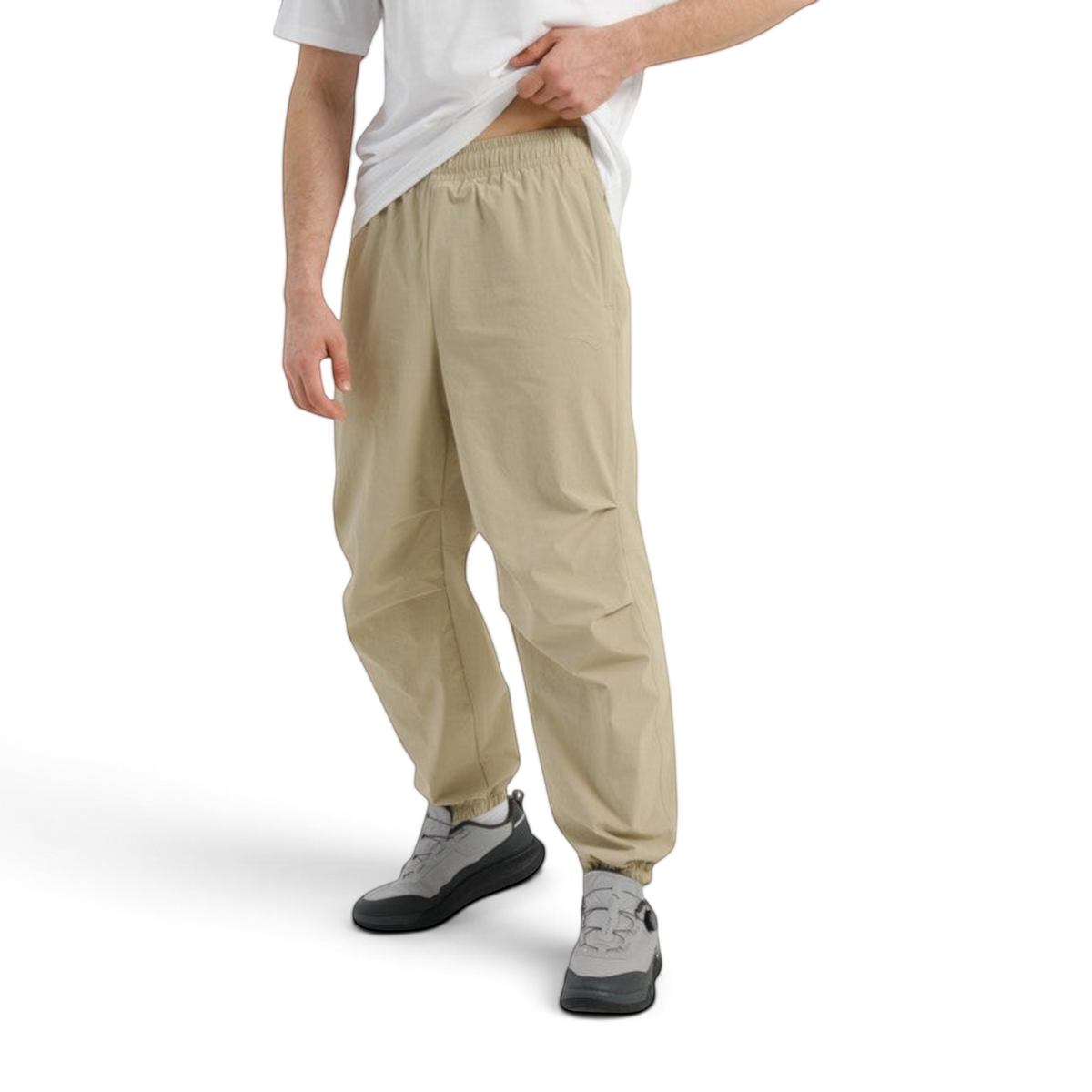 FRG COMMUTE relaxed beige woven track pants with an elastic waistband and cuffed ankles worn by a man