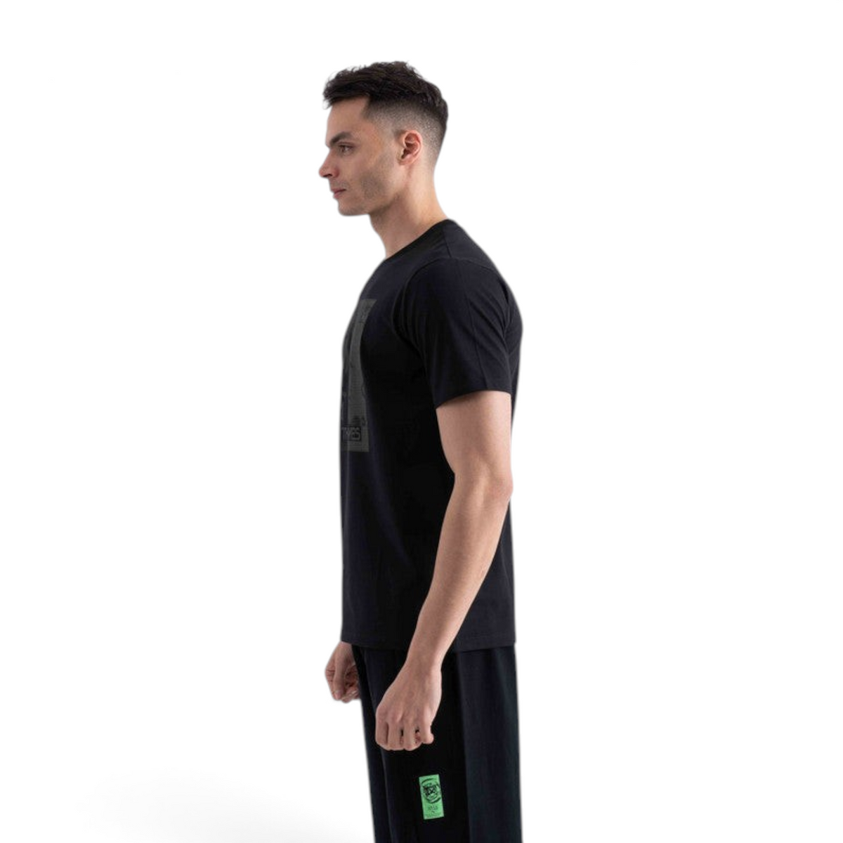 A man wearing a black FRG SS TEE short-sleeve shirt, viewed from the side against a white background.