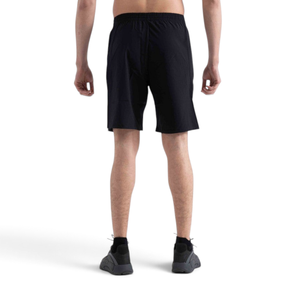 Back view of a man wearing black FRG athletic shorts with an elastic waistband, paired with black sneakers.