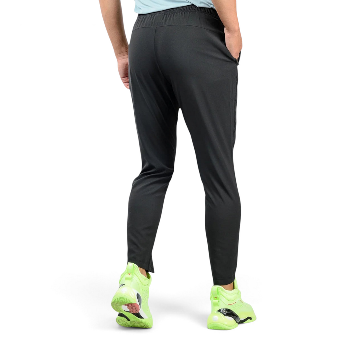 Back view of FRG ankle pants in black, featuring a tapered fit and zippered pockets, worn with neon green sneakers.