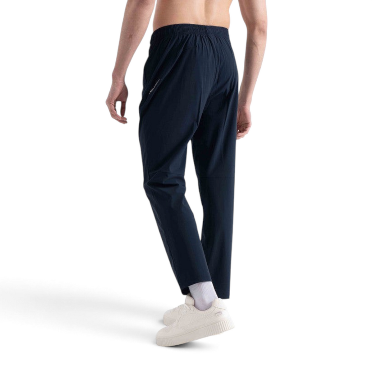 FRG navy blue knit track pants on a male model, featuring an elastic waistband and athletic fit, back view.