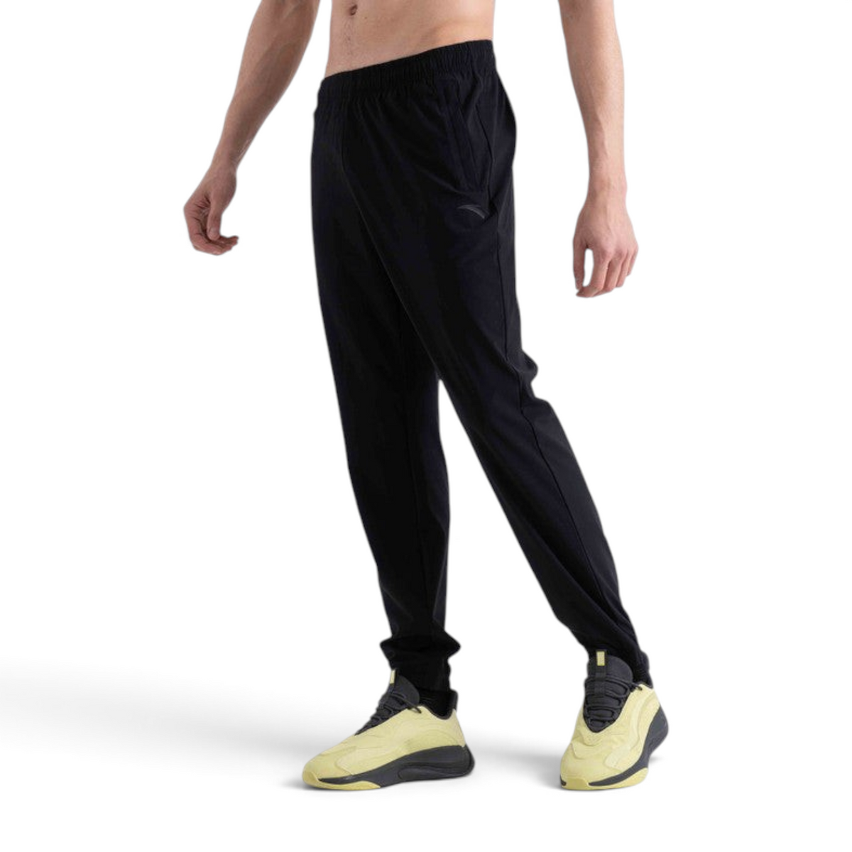 FRG black knit track pants with an elastic waistband and tapered fit worn by a model with yellow athletic sneakers