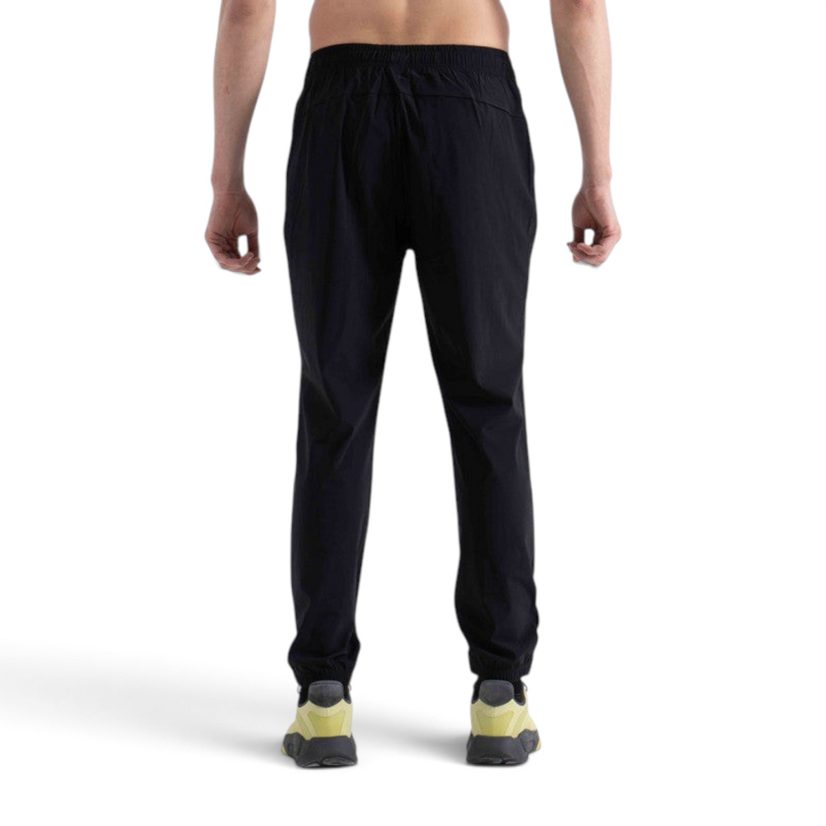 Back view of a man wearing FRG black knit track pants with an elastic waistband and cuffed ankles
