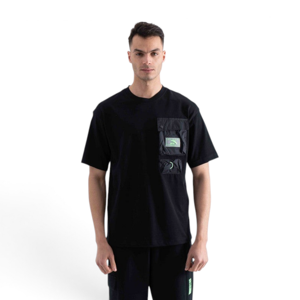 Model wearing a black FRG SS TEE with a technical chest pocket featuring green accents and a crew neckline