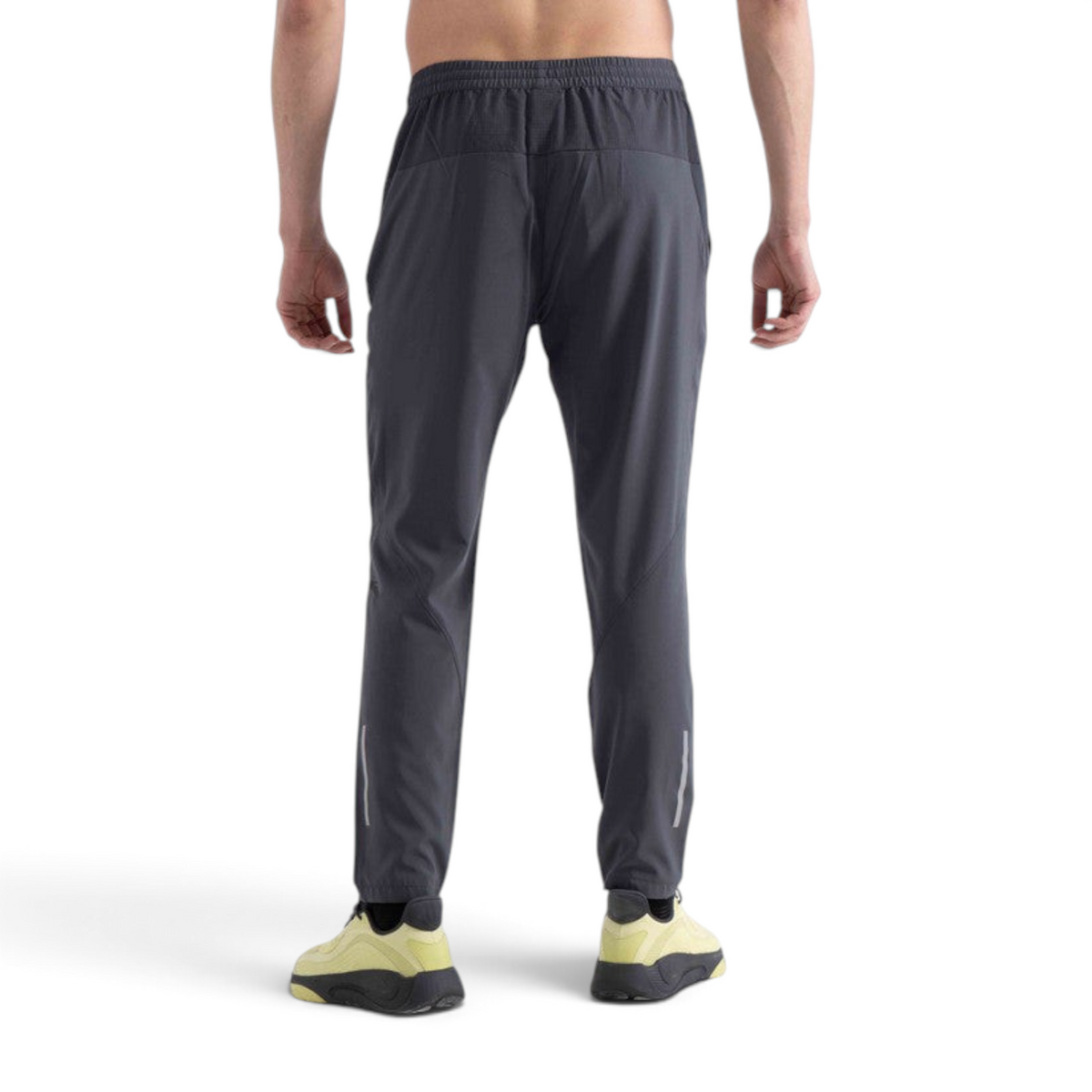 Back view of a man wearing FRG charcoal grey woven running track pants with reflective detailing on the calves.