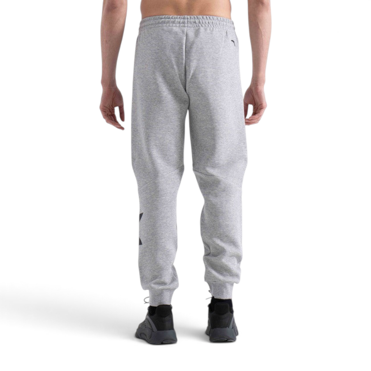 Back view of a person wearing grey FRG knit track pants with ribbed cuffs and a black logo detail