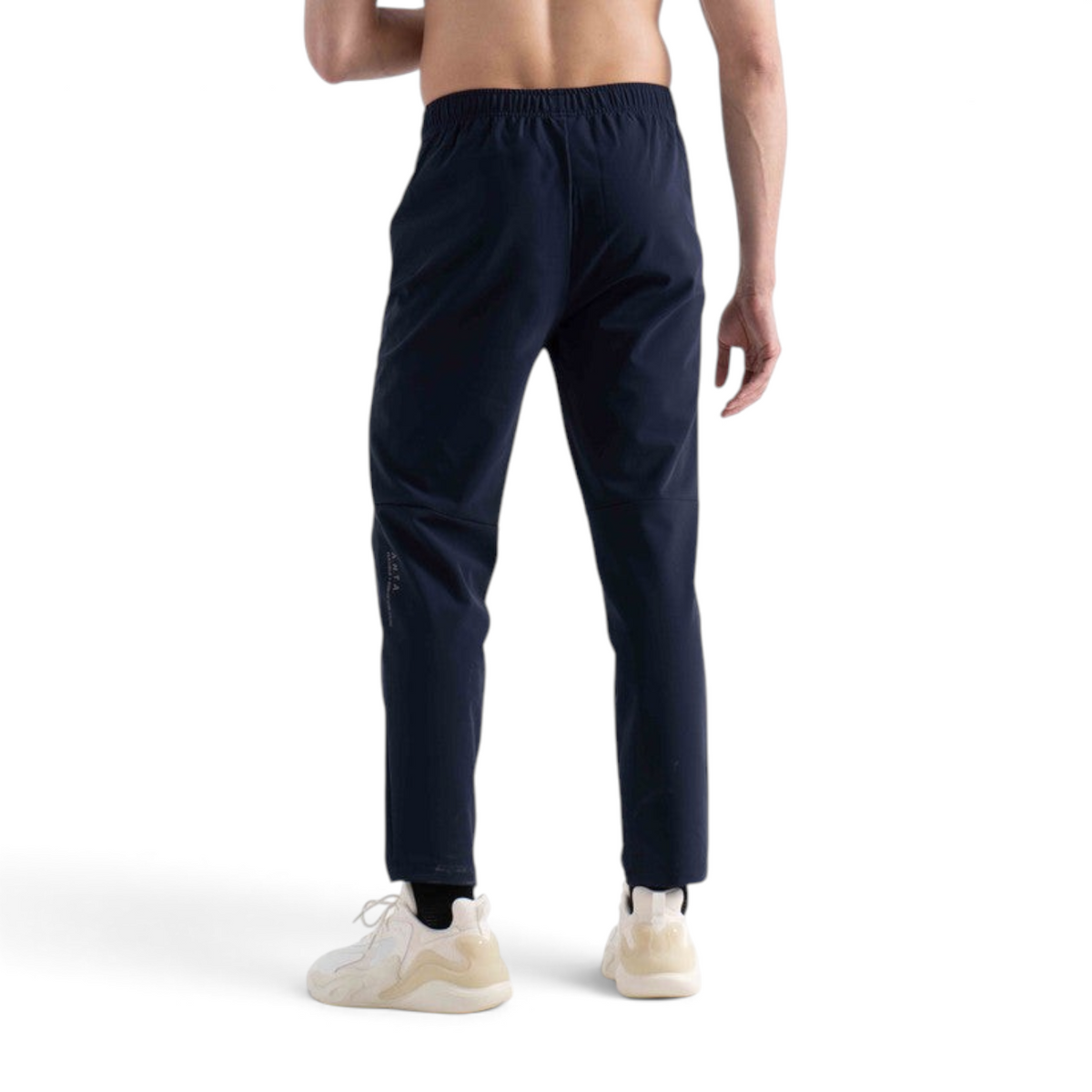 Back view of a man wearing navy blue FRG knit track pants with a slim fit and elastic waistband