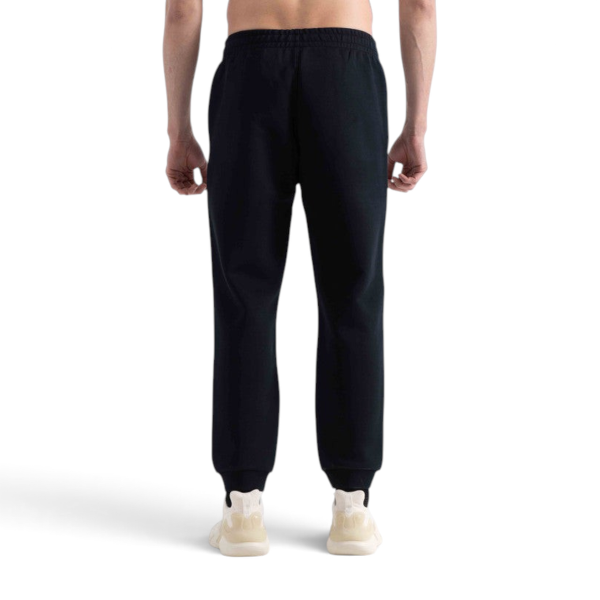 Back view of a person wearing black FRG knit track pants with cuffed ankles, isolated on a white background.