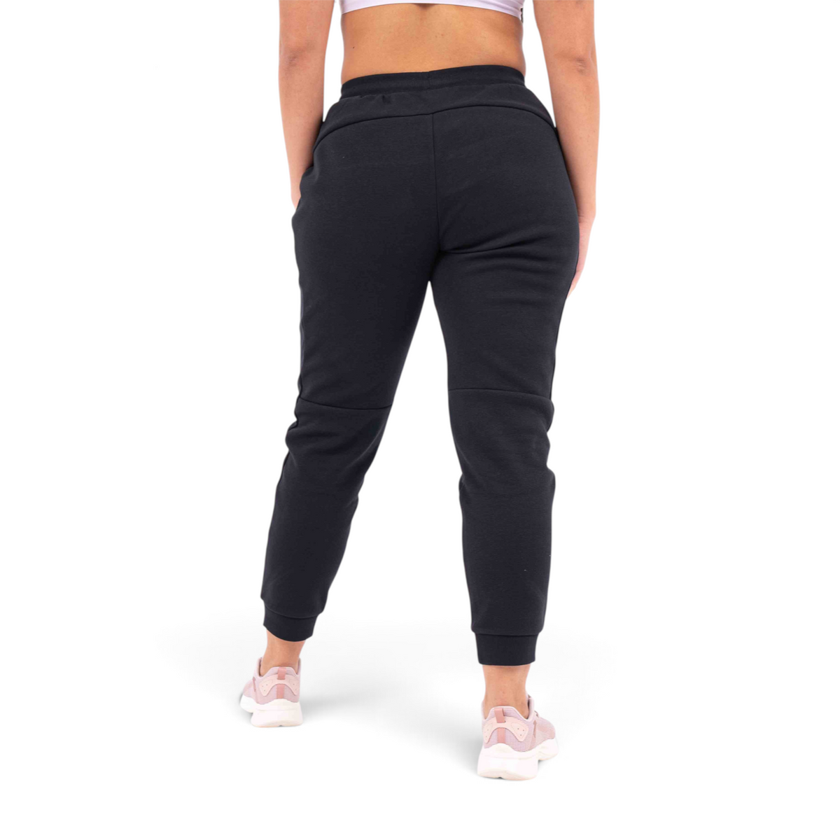 FRG black knit track pants with a regular fit, shown from the back on a model wearing pink sneakers.