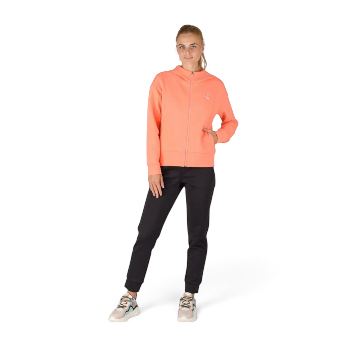 FRG model wearing ANTA black knit track pants and a coral zip-up hoodie with athletic sneakers