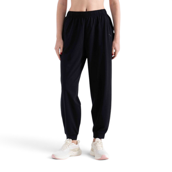 FRG black knit ankle pants with an elastic waistband and cuffs worn by a model with white sneakers