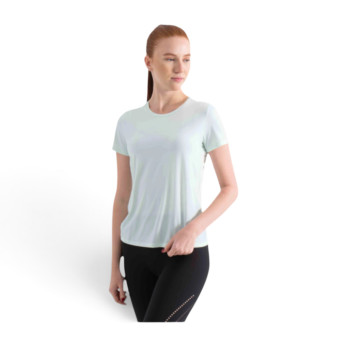 A woman wearing a light mint green FRG short sleeve t-shirt paired with black athletic leggings.