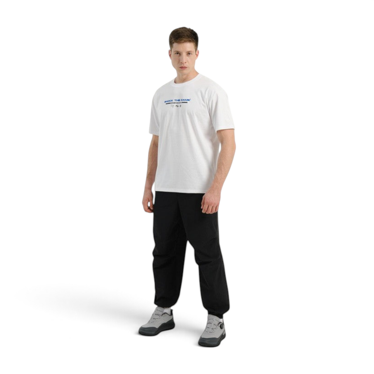 A man wearing FRG COMMUTE relaxed black woven textile trousers with a white t-shirt and grey sneakers.