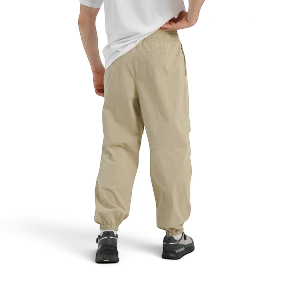 Back view of FRG COMMUTE relaxed beige woven track pants with elasticated cuffs worn by a model.