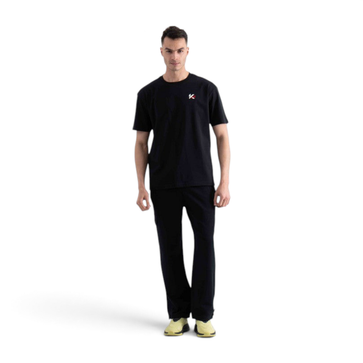 A man wearing a black FRG short-sleeve t-shirt with a small logo on the chest and matching black trousers.