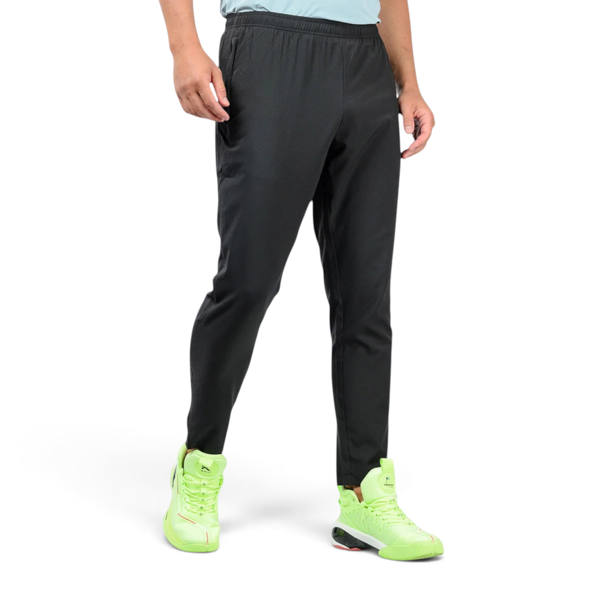 FRG black ankle pants with an elastic waistband worn by a man with bright neon green athletic sneakers