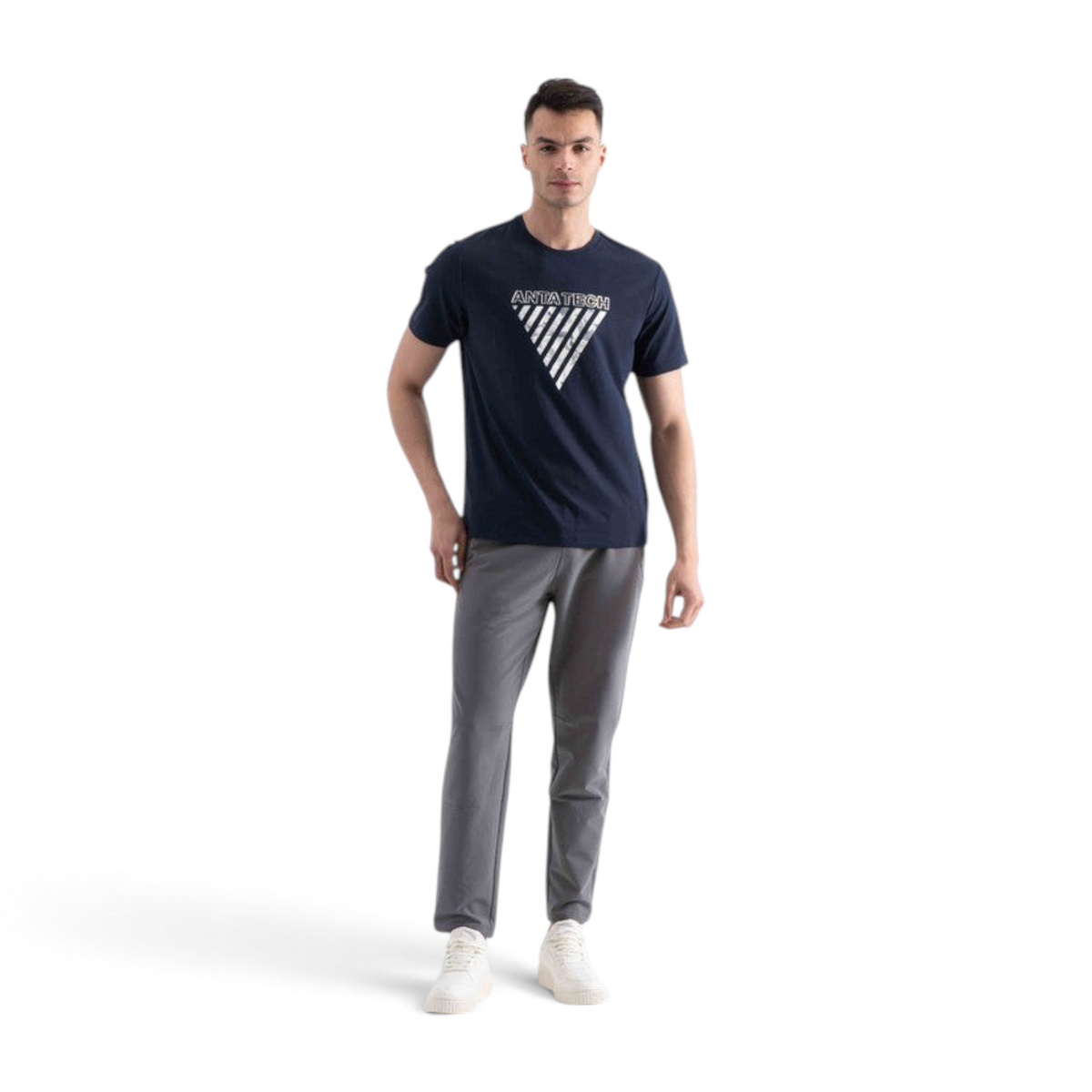 A man wearing a navy blue FRG SS TEE with a white triangular Antatech graphic print, paired with grey trousers.