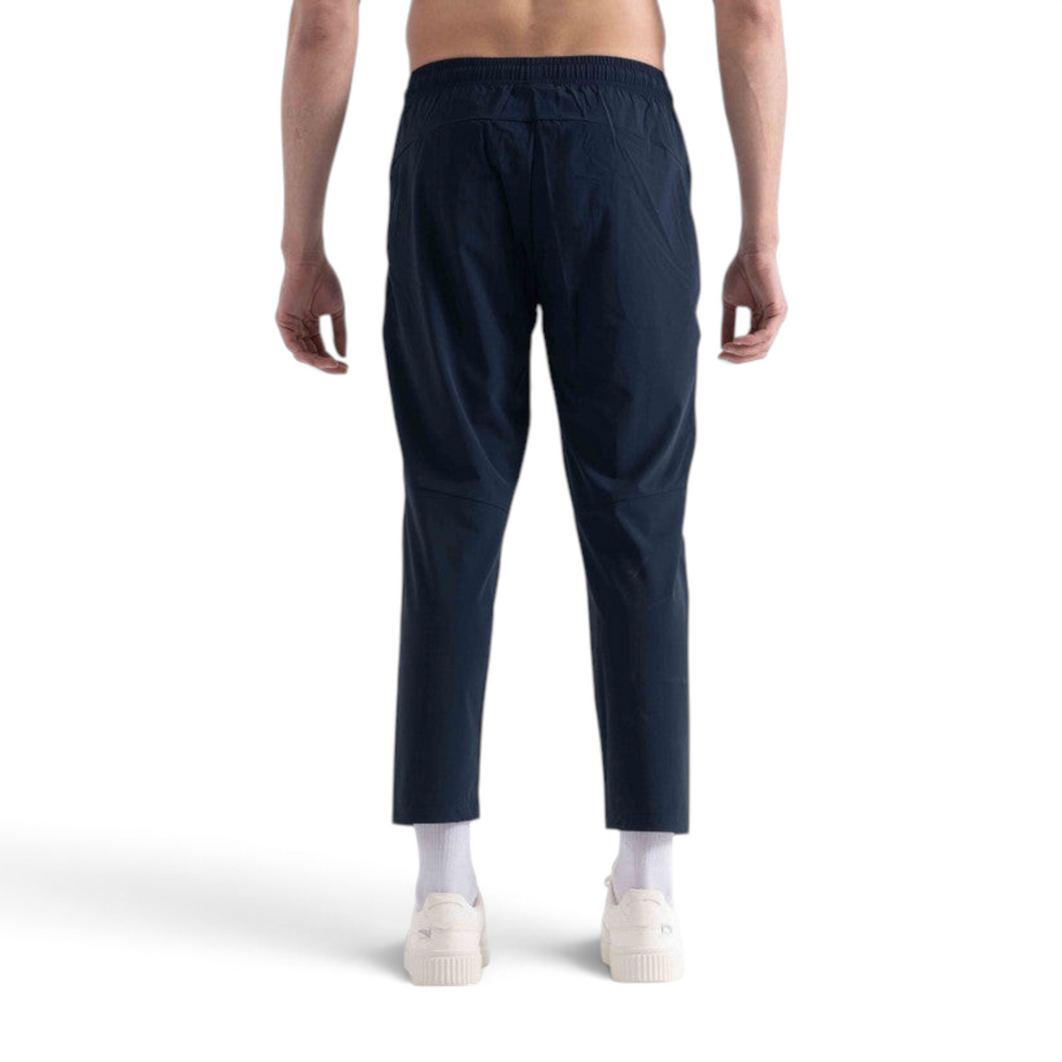 Back view of a man wearing FRG navy blue ankle pants with an elastic waistband, paired with white sneakers.