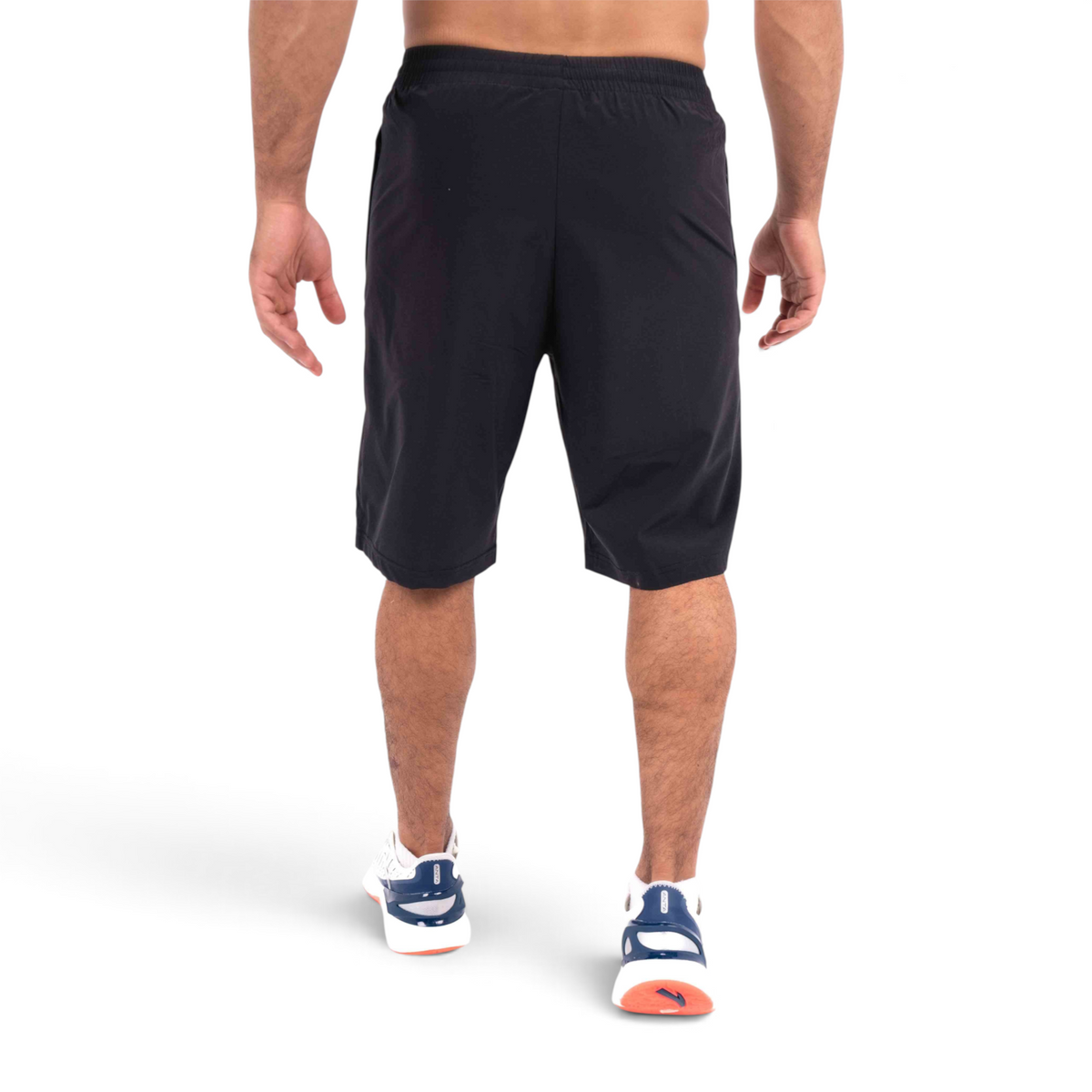 Back view of a man wearing black FRG athletic half pants with an elastic waistband, isolated on white background.