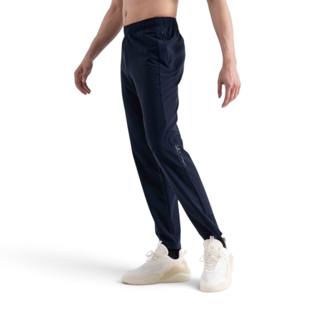 FRG navy blue knit track pants with an elastic waistband and side pocket, worn by a man with white sneakers.