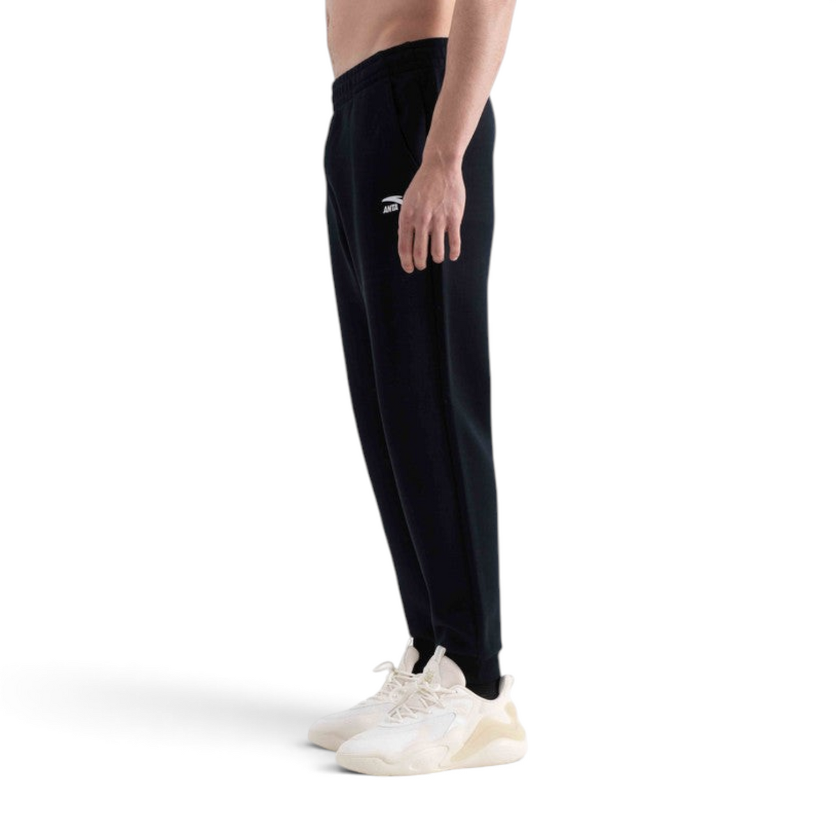 FRG knit track pants in black with a tapered fit and white logo detail worn by a man with light-colored sneakers