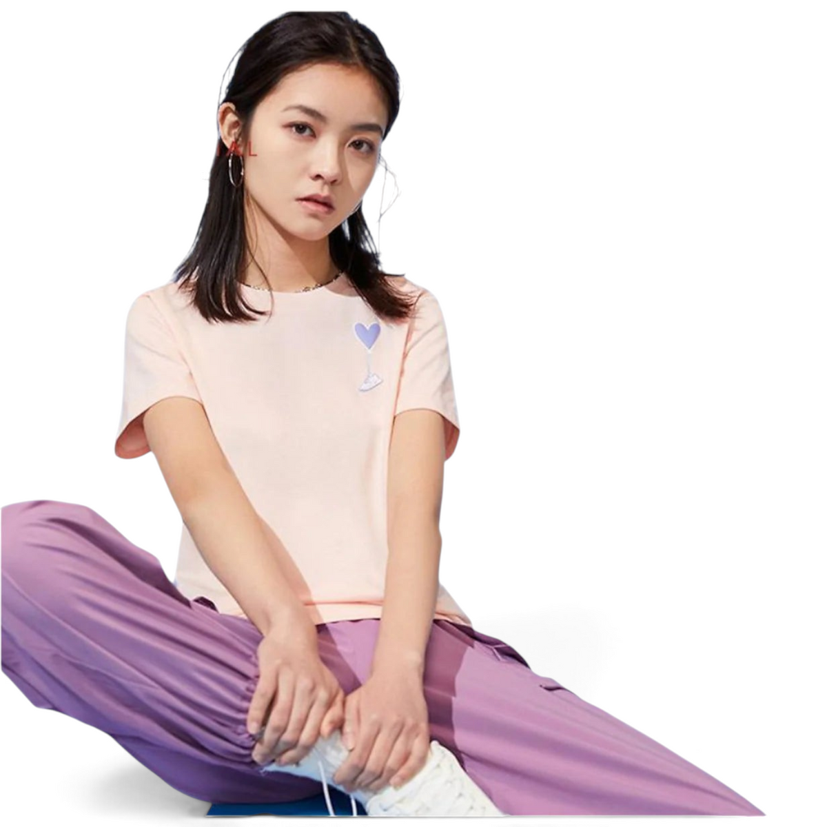 FRG light pink t-shirt with a small purple heart graphic worn by a young woman with purple cargo pants
