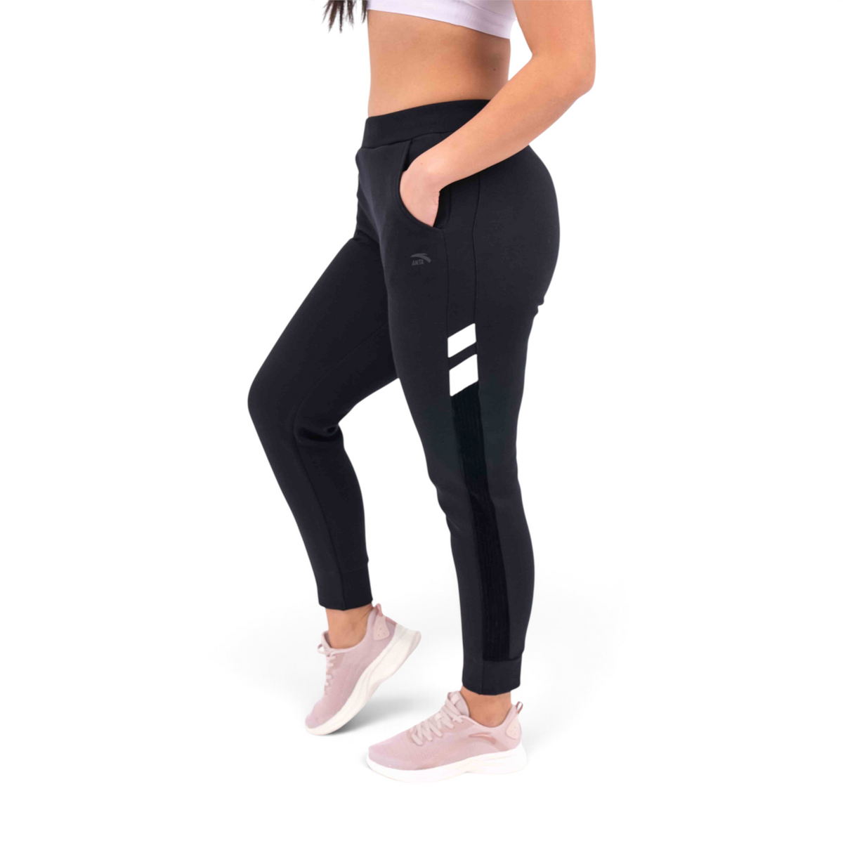 FRG knit track pants in black with white side stripe detail and regular fit, worn by a model with pink sneakers.