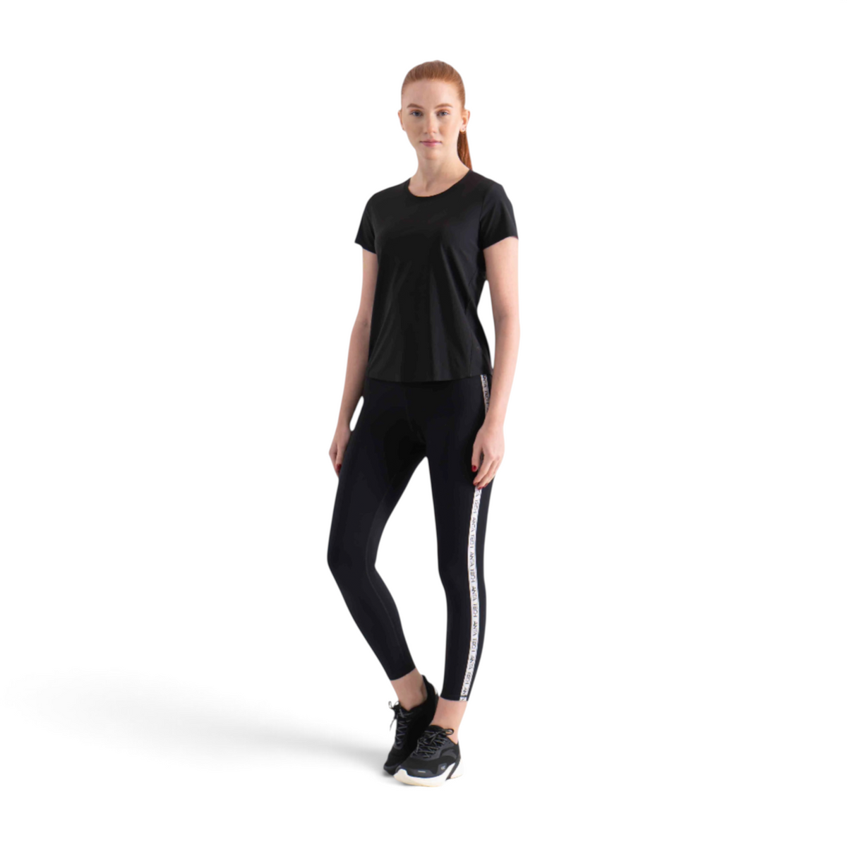 FRG black short sleeve athletic t-shirt worn by a woman with matching black leggings and sneakers