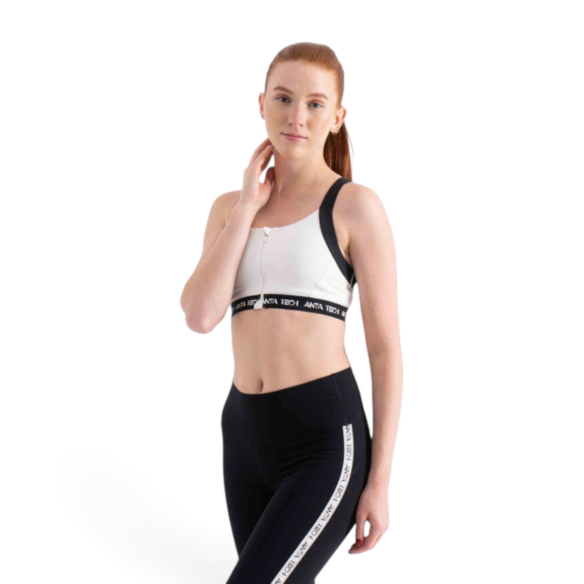 FRG model wearing a white zip-front sports bra and black leggings with branded elastic bands